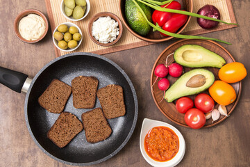 Cooking vegan vegetarian sandwiches with different vegetables and toasts of rye fried bread on kitchen. Healthy diet food concept