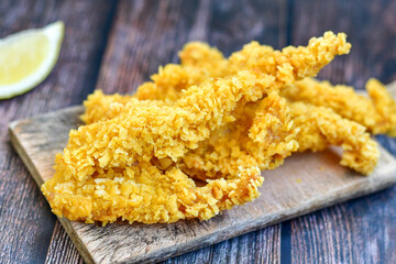 
 Crispy  deep fried   chicken strips. Breaded  with cornflakes chicken  breast fillets  with chilly peppers and fresh   basil on wooden rustic background