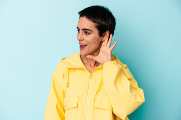 Fototapeta premium Young caucasian woman isolated on blue background trying to listening a gossip.