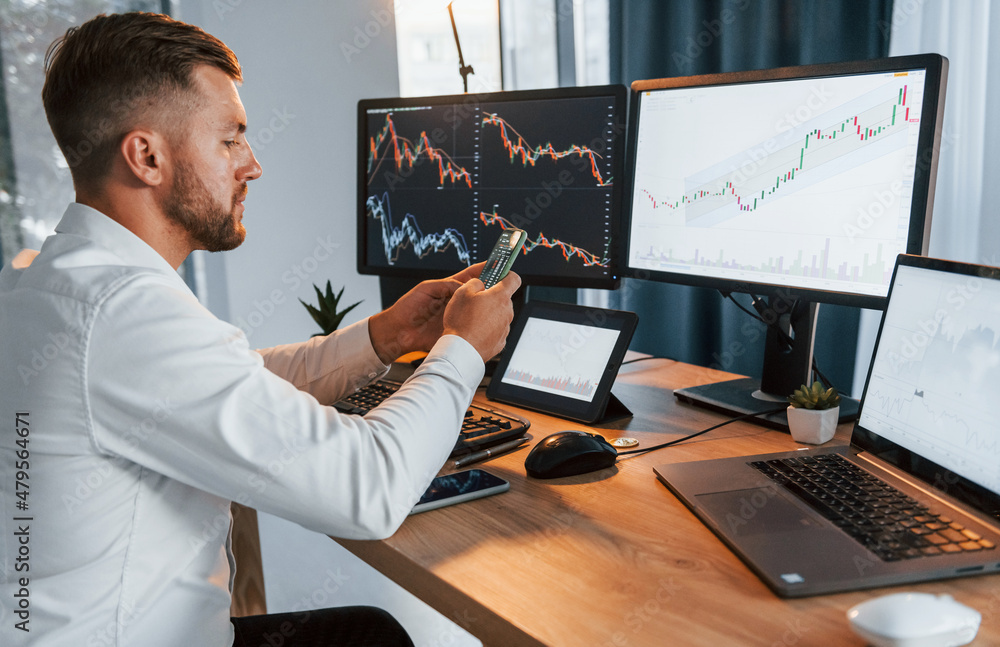Poster graphs and diagrams. young businessman in formal clothes is in office with multiple screens