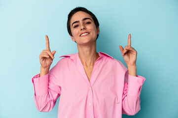 Young caucasian woman isolated on blue background indicates with both fore fingers up showing a...