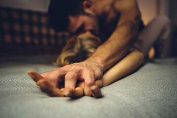 Close up image of intimate couple holding hands while having sex on bed - Boyfriend and girlfriend enjoying sensual foreplay on bedroom - Love concept