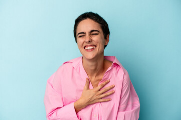 Obraz premium Young caucasian woman isolated on blue background laughs out loudly keeping hand on chest.
