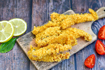 
 Crispy  deep fried   chicken strips. Breaded  with cornflakes chicken  breast fillets  with chilly peppers and fresh   basil on wooden rustic background