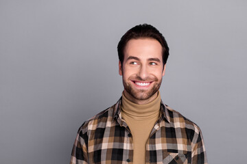 Photo of thoughtful funny guy dressed checkered shirt looking empty space smiling isolated grey color background