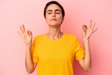 Young caucasian woman isolated on blue background relaxes after hard working day, she is performing yoga.