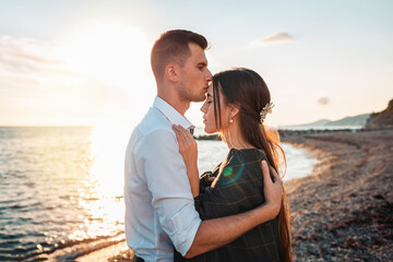 Love and kiss. Husband kisses and hugs his wife. In the background, the ocean and the sunset. Just married concept