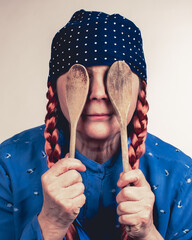 Crazy mature chef woman with red pigtails covered his eyes with two wooden spoons. She is crazy...
