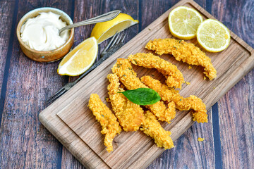 
 Crispy  deep fried   chicken strips and wedges potato. Breaded  with cornflakes chicken  breast fillets  with chilly peppers and fresh   basil on wooden rustic background