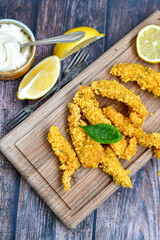 
 Crispy  deep fried   chicken strips and wedges potato. Breaded  with cornflakes chicken  breast fillets  with chilly peppers and fresh   basil on wooden rustic background