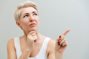 Portrait of a thoughtful adult woman pointing her finger into space. Copy space. The concept of psychology and business