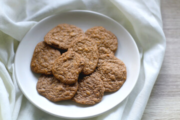 Plate of healthy, gluten free and high protein cookies, made with bananas, eggs, chia seeds and almonds. White tablecloth and wooden background. Selective focus.