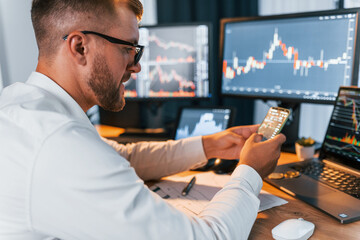 Fototapeta premium Many monitors. Young businessman in formal clothes is in office with multiple screens