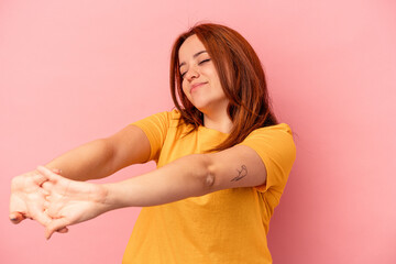 Young caucasian woman isolated on pink background stretching arms, relaxed position.