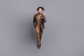 Photo of positive attractive guy dressed checkered shirt jumping high running fast isolated grey color background