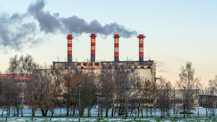 Obraz premium Industrial air pollution. Winter landscape with factory and trees. The concept of environmental pollution.