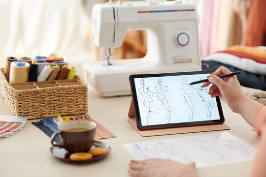 Woman drawing fashion sketches for new collection on tablet computer