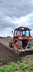 Fototapeta premium Farmer in tractor preparing land with seedbed cultivator as part of pre seeding activities in early spring season of agricultural works at farmlands, vertical view.