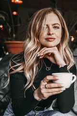 Close up portrait of a woman in cafe. She is holding a cup of coffee.