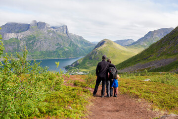 Happy family, standing on a rock and looking over Segla mountain on Senja island, North Norway....