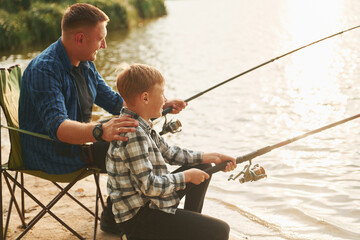 Resting and having fun. Father and son on fishing together outdoors at summertime