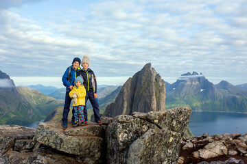 Happy family, standing on a rock and looking over Segla mountain on Senja island, North Norway....