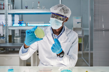 Fototapeta na wymiar African young scientist in protective wear taking sample during scientific experiment in the laboratory, he examining new virus
