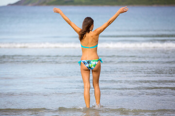 Woman, enjoying freezing cold water in Ersfjord Beach on Senja island, beautiful landscape view over mountains