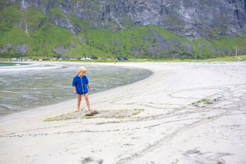 Children, playing on Ersfjords beach in Senja on a summer day, running and jumping in the sand and water, northern Norway