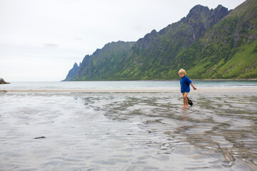 Children, playing on Ersfjords beach in Senja on a summer day, running and jumping in the sand and water, northern Norway