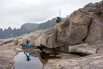 Child, having fun in Tungeneset, Senja, Norway, jumping over big puddle, making reflection in water