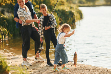 Middle sized lake. Father and mother with son and daughter on fishing together outdoors at...