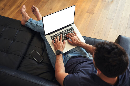 Man using laptop sitting on sofa with visible screen