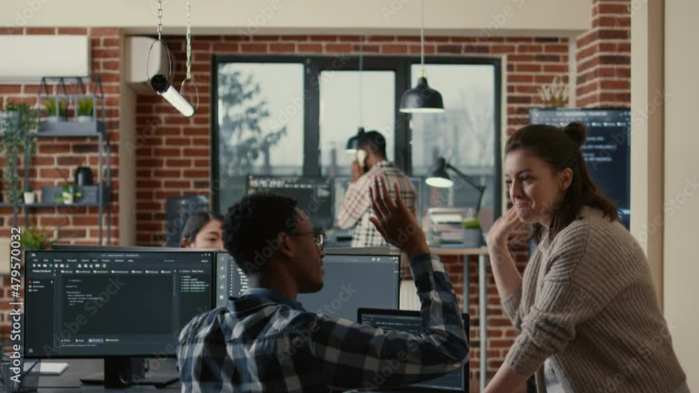 Poster two software developers doing high five hand gesture at desk with multiple screens running ai code c