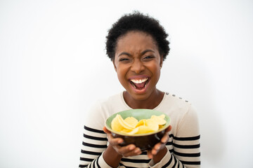 happy young African American woman holding bowl of chips by isolated white background