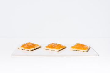 Mermelada de albaricoque sobre pan tostado en una mesa blanca y fondo claro