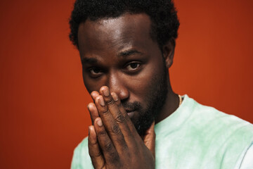 Young black man holding palms together and looking at camera