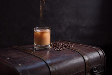 Vaso de café helado con canela y granos de café en una vieja maleta marrón	