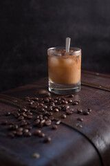Vaso de café helado con canela y granos de café en una vieja maleta marrón	