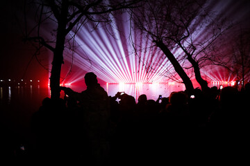 People watch and film a laser show over the lake during New Years celebrations in the Alexandru...