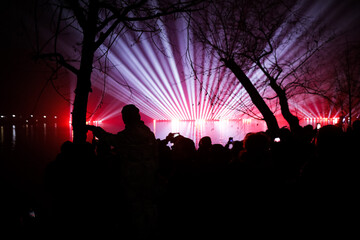 People watch and film a laser show over the lake during New Years celebrations in the Alexandru Ioan Cuza park in Bucharest.