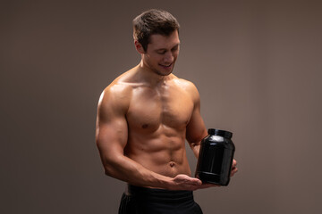 Waist up portrait view of sporty shirtless man holding bottle with healthy protein drink isolated...