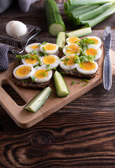 Sandwich with boiled egg on wooden cutting board