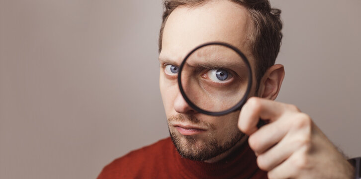 The man looking through a magnifier with suspicious