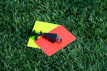 Referee soccer, football game whistle, red and yellow cards on green grass. Two penalty cards and a...