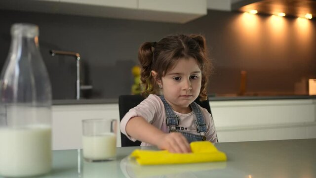The girl who wipes the milk with a kitchen towel that melted on the table when she put it in a crystal glass. Solution for small domestic accidents produced and arranged by children.