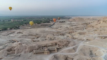 Fotobehang Balloons fly over the Valley of the Kings in Luxor. You can see the ongoing archaeological excavations, ancient buildings among the sandy desert. In the distance is the green valley of the Nile. Egypt © Вера 