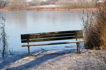 Eine Bank bietet an einem winterlichen Tag einen Ruheplatz an einem See