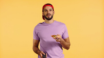 happy man with pizza watching tv isolated on yellow