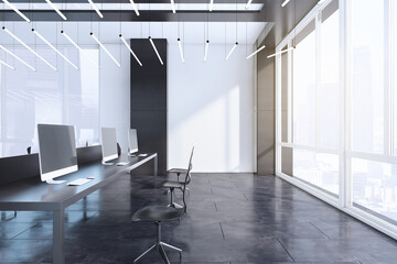 Modern concrete coworking office interior with window and bright city view, empty computer screens, equipment, furniture and daylight. 3D Rendering.